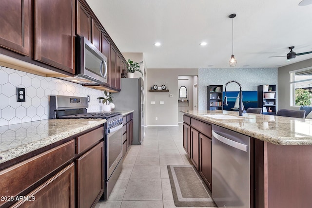 kitchen featuring light tile patterned floors, a sink, stainless steel appliances, tasteful backsplash, and open floor plan