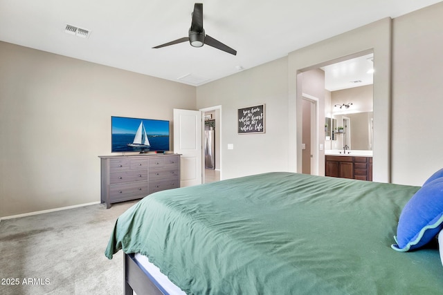 bedroom featuring visible vents, baseboards, light carpet, ensuite bathroom, and a sink