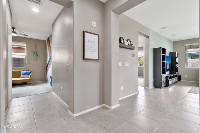 hall featuring light tile patterned floors and baseboards