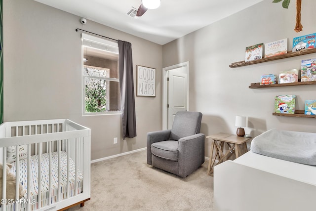 carpeted bedroom with visible vents, baseboards, a nursery area, and ceiling fan