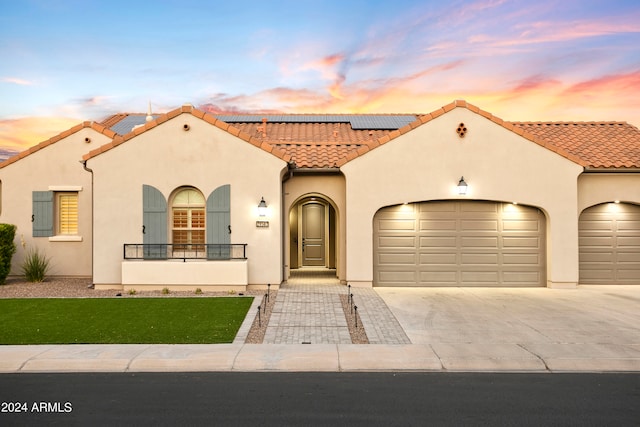 mediterranean / spanish home featuring a garage and a lawn