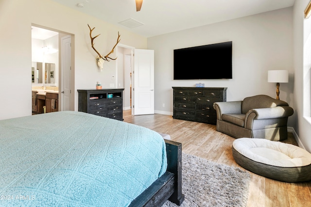 bedroom with light hardwood / wood-style floors, ensuite bathroom, and ceiling fan