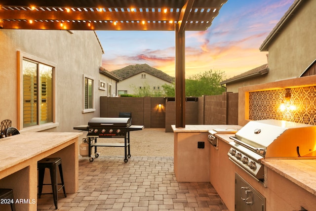 patio terrace at dusk with grilling area, area for grilling, and a bar