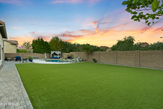 yard at dusk featuring a fenced in pool and a patio area