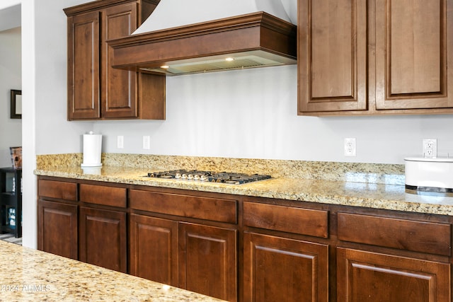 kitchen featuring light stone counters, stainless steel gas cooktop, and custom exhaust hood