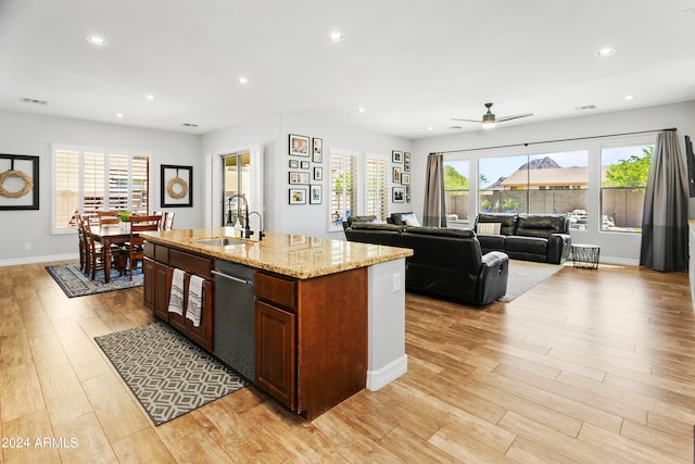 kitchen featuring a kitchen island with sink, ceiling fan, light stone countertops, and light hardwood / wood-style floors