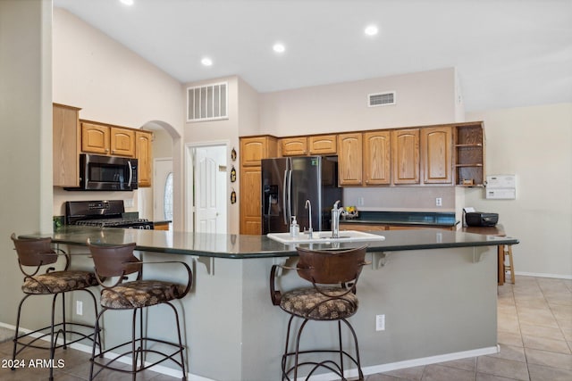 kitchen featuring kitchen peninsula, stainless steel appliances, light tile patterned floors, and a breakfast bar area