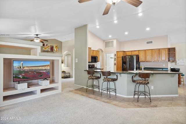 kitchen featuring light carpet, a breakfast bar, stainless steel appliances, and lofted ceiling