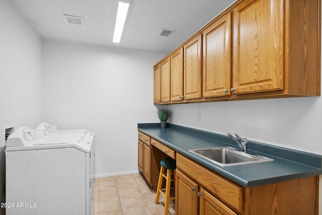 washroom with light tile patterned floors, sink, separate washer and dryer, and cabinets