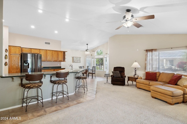 kitchen with vaulted ceiling, stainless steel fridge with ice dispenser, a kitchen bar, and plenty of natural light