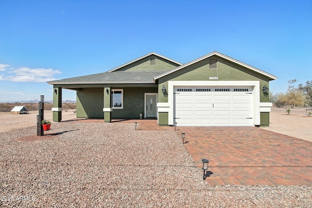 single story home featuring a garage, roof with shingles, decorative driveway, and stucco siding