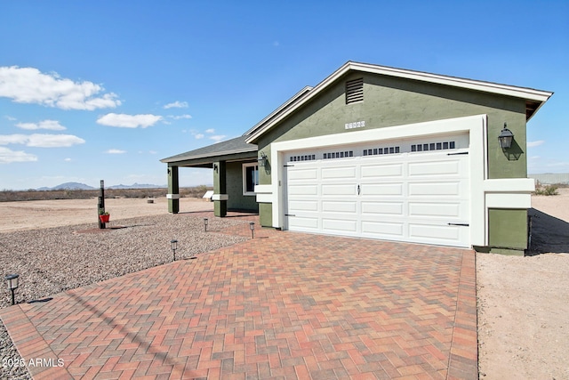 ranch-style home featuring decorative driveway, an attached garage, and stucco siding