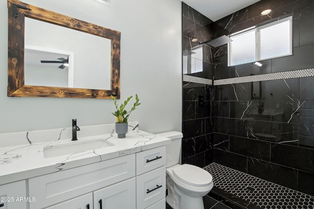 bathroom featuring tiled shower, ceiling fan, vanity, and toilet