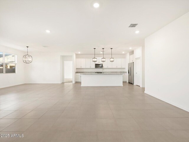 unfurnished living room featuring an inviting chandelier and light tile patterned flooring