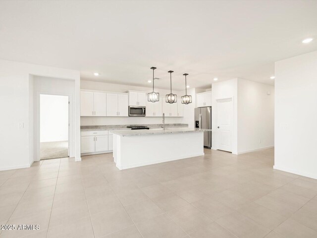 kitchen featuring pendant lighting, a kitchen island with sink, white cabinets, light stone counters, and stainless steel appliances