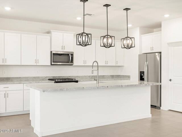 kitchen featuring white cabinetry, hanging light fixtures, light stone counters, a kitchen island with sink, and appliances with stainless steel finishes