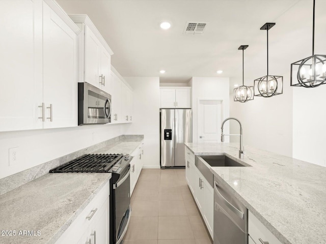 kitchen featuring white cabinetry, sink, light stone countertops, hanging light fixtures, and appliances with stainless steel finishes