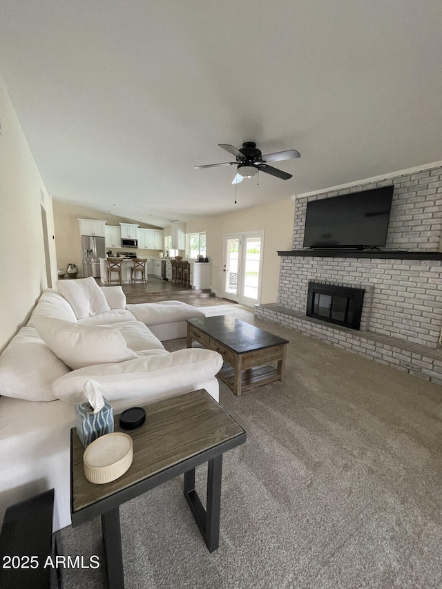 carpeted living area featuring ceiling fan and a fireplace