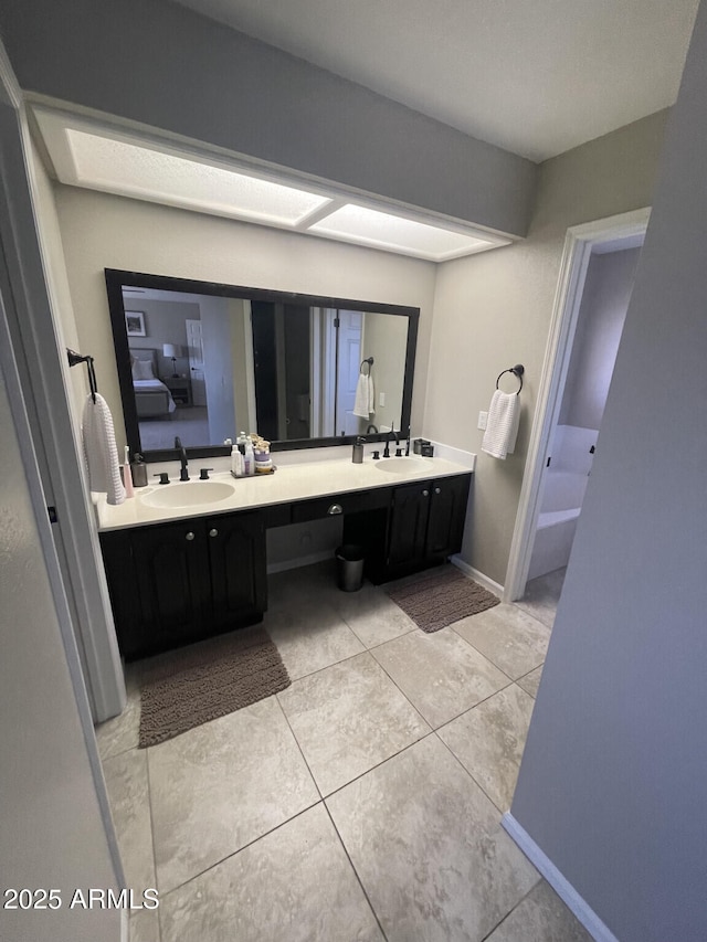 bathroom with double vanity, baseboards, and a sink