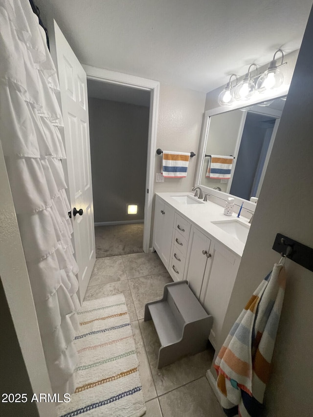 full bath with a sink, double vanity, and tile patterned floors