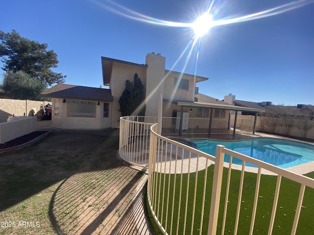 rear view of property featuring a yard, a fenced in pool, a fenced backyard, and stucco siding