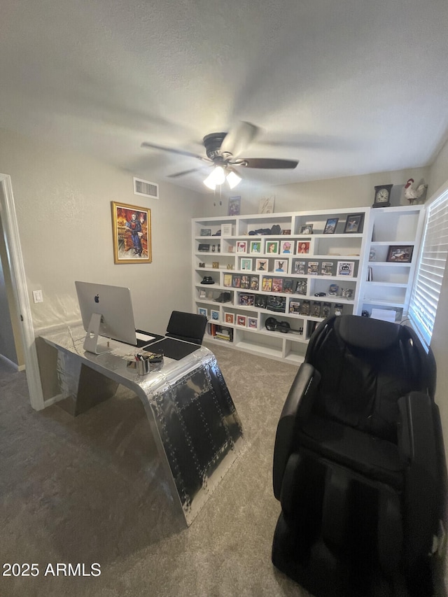 carpeted office space featuring visible vents, a textured ceiling, and a ceiling fan