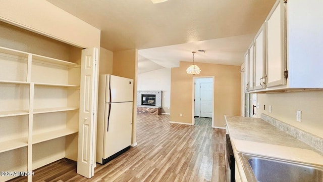 kitchen with freestanding refrigerator, white cabinetry, vaulted ceiling, light wood-style floors, and light countertops