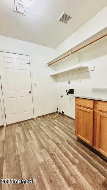 laundry area featuring cabinet space, hookup for a washing machine, light wood finished floors, and hookup for an electric dryer