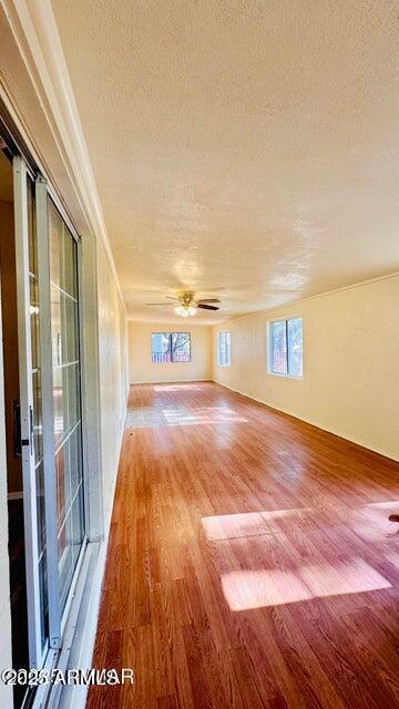 empty room featuring a textured ceiling, light wood-type flooring, and crown molding
