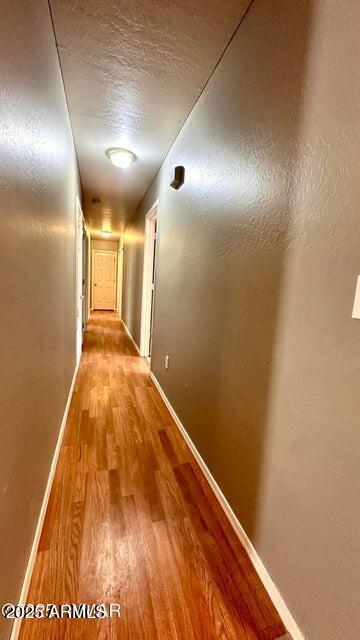 corridor with wood finished floors and baseboards
