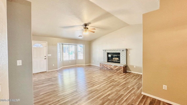 unfurnished living room with a ceiling fan, baseboards, wood finished floors, vaulted ceiling, and a fireplace
