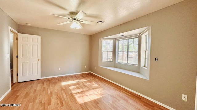 unfurnished room with wood finished floors, baseboards, and ceiling fan