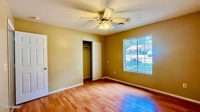 unfurnished bedroom with light wood-type flooring, baseboards, a closet, and ceiling fan