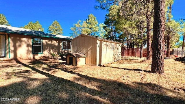 back of house featuring a storage unit, a fenced backyard, and an outbuilding