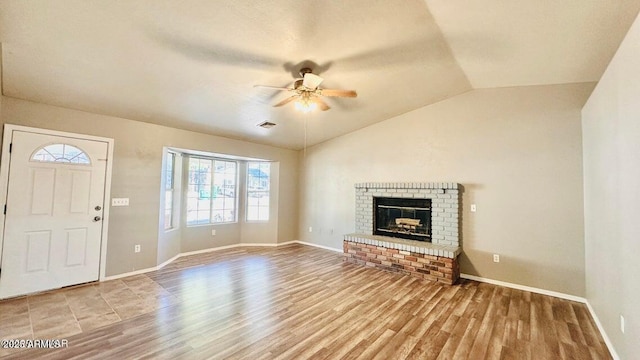unfurnished living room with wood finished floors, ceiling fan, vaulted ceiling, baseboards, and a fireplace