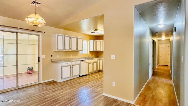kitchen featuring dishwasher, light wood finished floors, light countertops, baseboards, and lofted ceiling