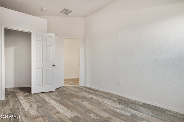 unfurnished bedroom with a closet, hardwood / wood-style flooring, and lofted ceiling