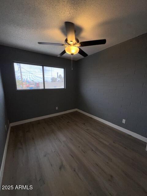 spare room featuring a textured ceiling, ceiling fan, wood finished floors, and baseboards