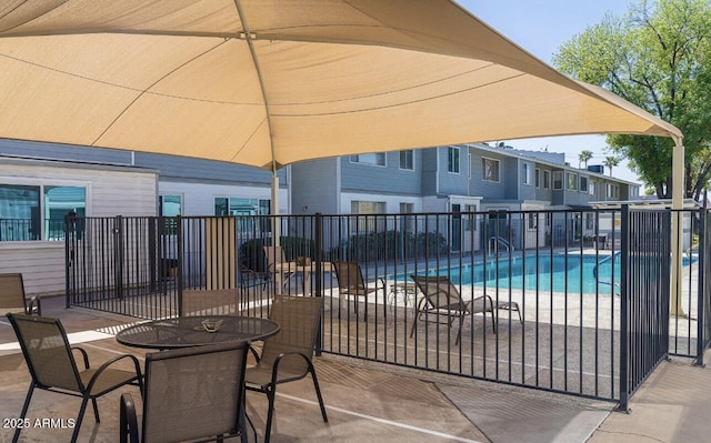 view of patio with outdoor dining space, fence, and a community pool