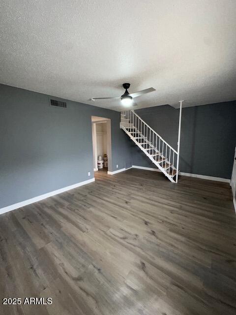 spare room featuring a textured ceiling, ceiling fan, wood finished floors, visible vents, and baseboards