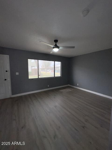 unfurnished room with a ceiling fan, baseboards, and wood finished floors