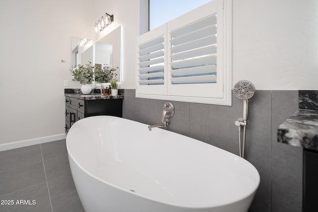 bathroom with a freestanding bath, vanity, and tile patterned floors