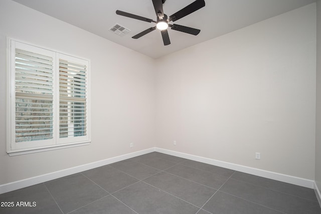 empty room featuring ceiling fan, baseboards, and dark tile patterned floors