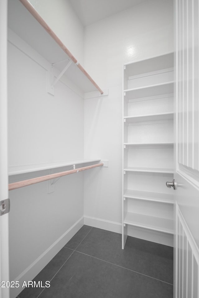 spacious closet featuring dark tile patterned flooring