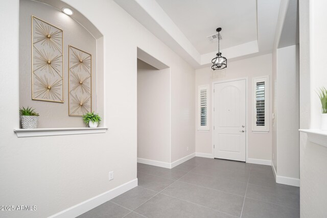 tiled entrance foyer featuring baseboards and a raised ceiling