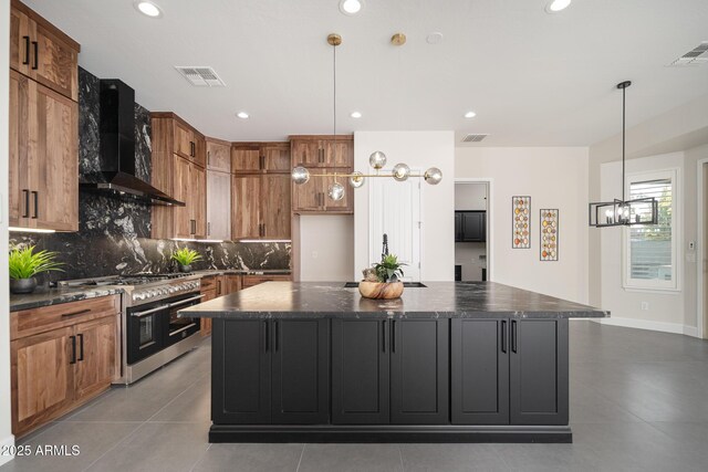 kitchen with wall chimney range hood, double oven range, brown cabinetry, backsplash, and a large island