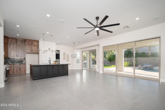 kitchen with open floor plan, dark countertops, a ceiling fan, backsplash, and recessed lighting