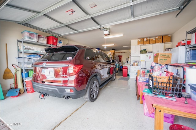 garage with a garage door opener and white refrigerator