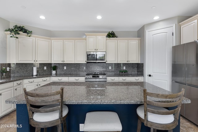 kitchen featuring a kitchen bar, dark stone countertops, a center island, and stainless steel appliances