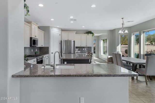 kitchen featuring hanging light fixtures, stainless steel appliances, tasteful backsplash, kitchen peninsula, and plenty of natural light